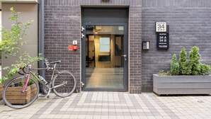 A modern building entrance with a glass door, a sign indicating the address, and a bicycle parked outside. - Kalwaryjska Elegant Stay Studio 18B (Kraków)