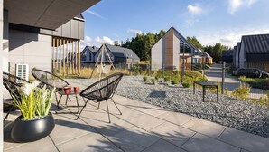 Eine moderne Außenpatio mit Sitzgelegenheit, einer Schaukel und Blick auf Wohnhäuser.