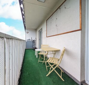 A balcony with artificial green flooring, a white table, and two wooden chairs. - Reymonta Vivid Space Apartment (Wrocław)