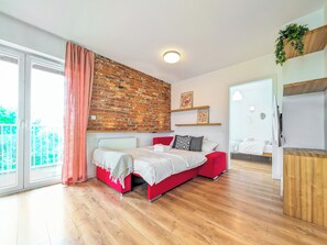 A modern bedroom with a brick wall, a red bed, and a wooden floor. - Reymonta Vivid Space Apartment (Wrocław)