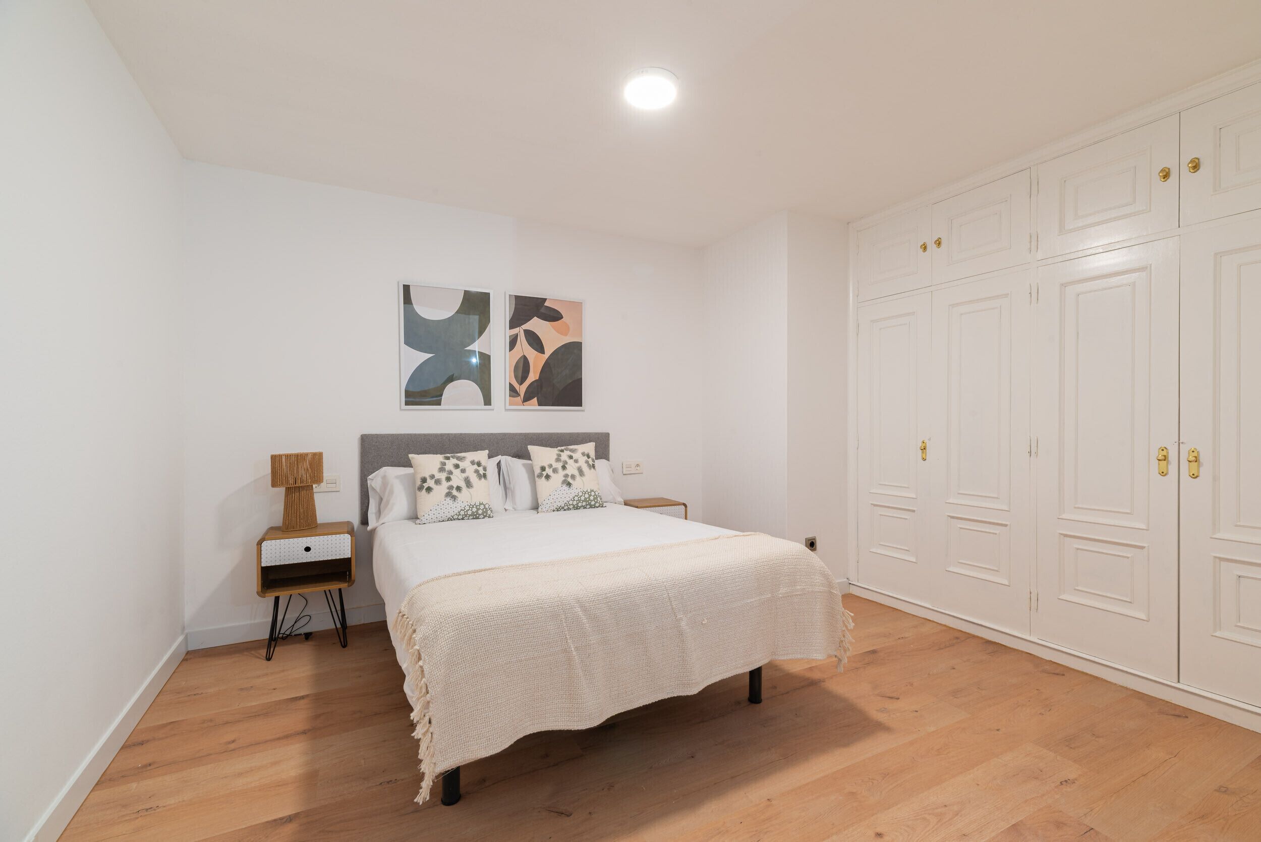 Un dormitorio con cama, mesita de noche, lámpara y armario.