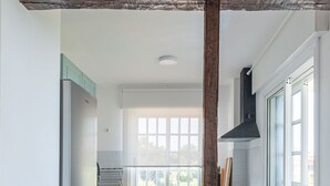Cocina moderna con una isla de madera, dos taburetes y vistas al comedor.