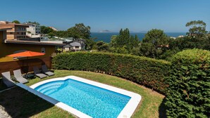 Una piscina con sillones de descanso y vista al mar.