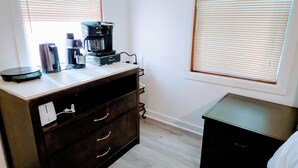Une pièce comprenant une commode en bois foncé, une machine à café et un petit meuble noir.