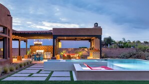Une terrasse extérieure moderne, dotée d’une piscine, de coins salon et d’un espace barbecue.