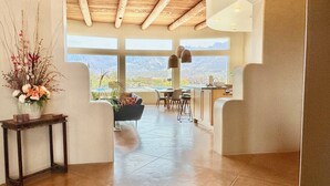 Un intérieur spacieux avec un plafond haut, de grandes fenêtres et une vue sur l’extérieur.