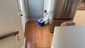 A wooden staircase leading to a kitchen area with a stainless steel refrigerator and a blue trash bin. - Charming 1-bedroom house in fabulous Hamburg (Hamburg)