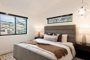 A bedroom with a bed, nightstands, a window, and a wall-mounted light fixture.