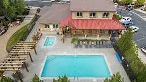 A hotel with a swimming pool, outdoor seating, and a covered patio area.