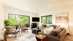 A modern living room with a large sofa, a coffee table, and a TV mounted on the wall. - Bear Hollow Basecamp, Hot Tub, Balconies, Pool Clubhouse (Park City)