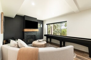 Una sala de estar moderna con chimenea, un sofá, una mesa de centro y un ventanal grande.