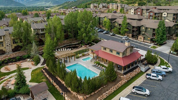 A residential area with a swimming pool, multiple-story buildings, and a mountainous backdrop.