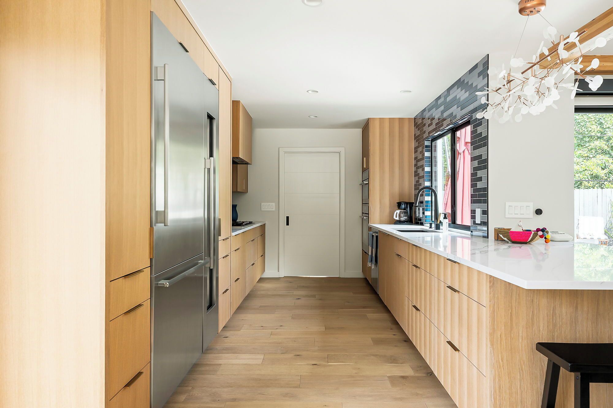A modern kitchen with wooden cabinets, a stainless steel refrigerator, and a large island with a sink.