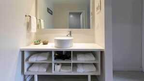 A modern bathroom with a white vanity, a large mirror, and shelves for towels and toiletries. - Magical Studio for 4 Shuttle to Disney (Kissimmee)
