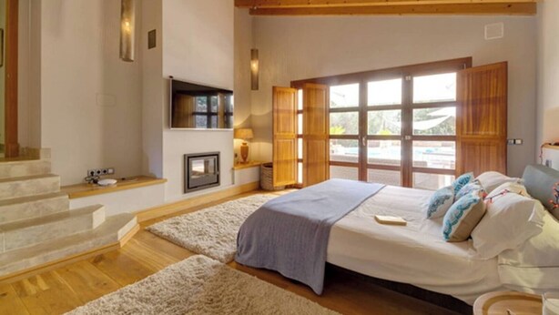 Ein Schlafzimmer mit Bett, Fernseher, Fenster und Treppe.