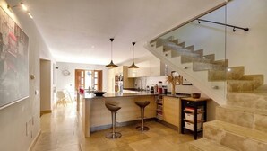 Eine moderne Küche mit Kochinsel, Barhocker und einer Treppe mit Glastrennwand.