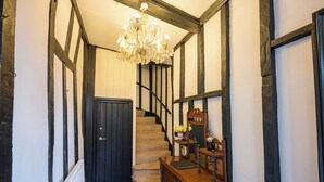 Un escalier avec une rampe en bois, un lustre et un meuble en bois doté d’un miroir.