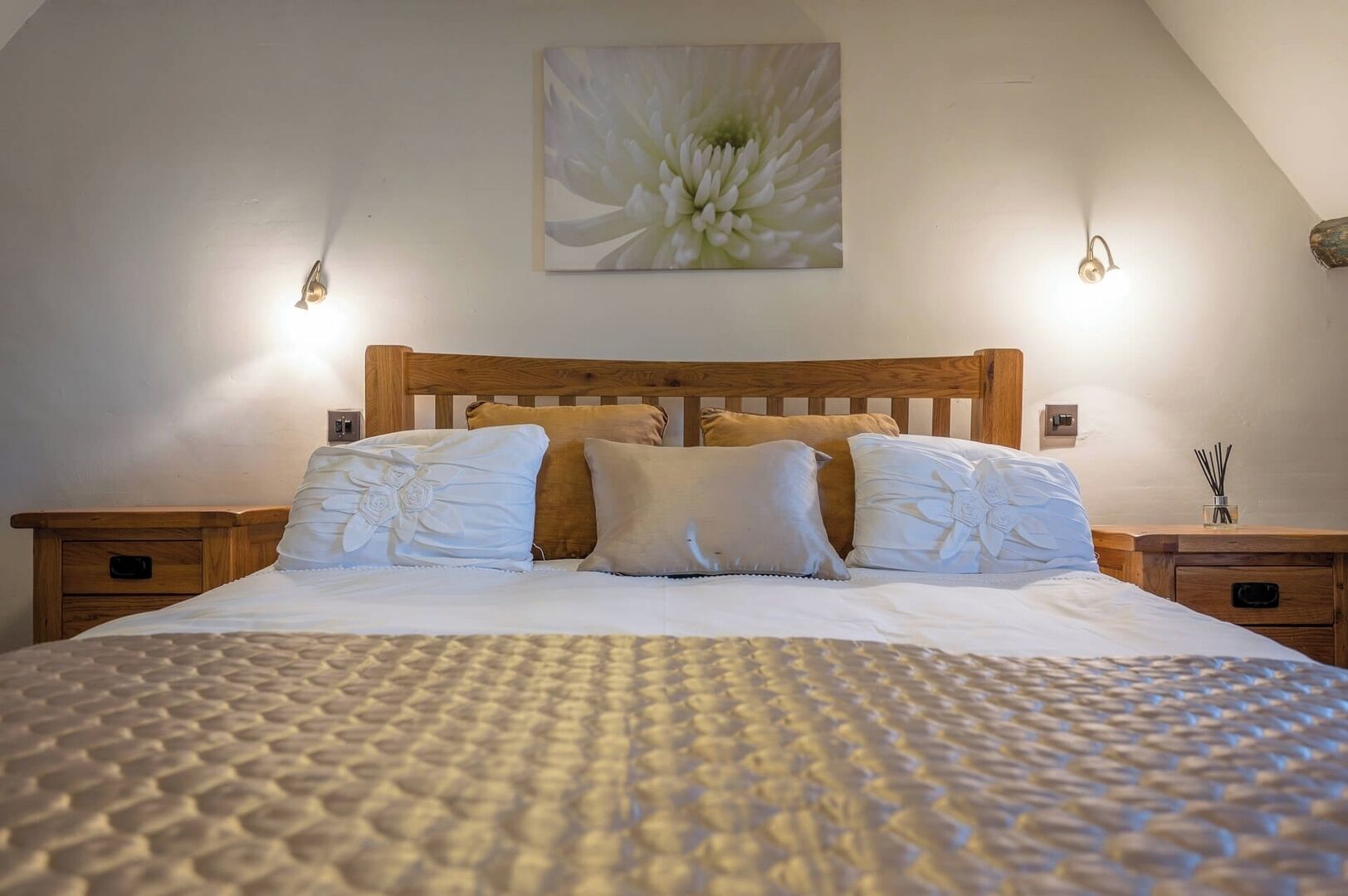 A neatly made bed with a textured blanket, a wooden headboard, and two bedside tables with lamps.