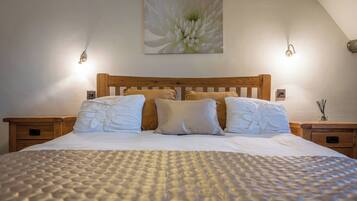 A neatly made bed with a textured blanket, a wooden headboard, and two bedside tables with lamps.
