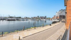 Un puerto deportivo con barcos amarrados, cielo despejado y edificios al fondo.