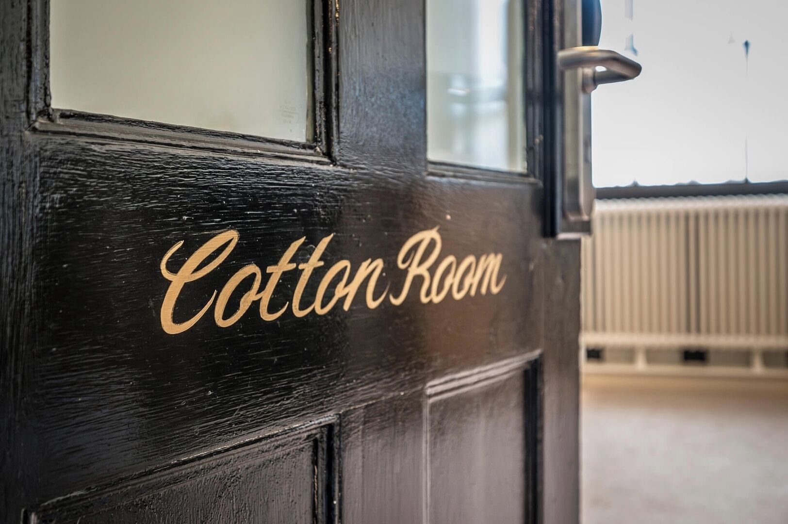 Una puerta con la inscripción 'Cotton Room' en letras doradas.