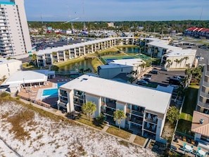 Hotel com vários andares e área de piscina, próximo a uma praia.
