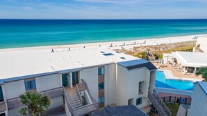 A hotel with a pool, a beach view, and a clear sky.
