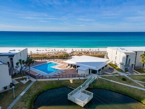 A resort with a swimming pool, a covered patio, and a view of the ocean.