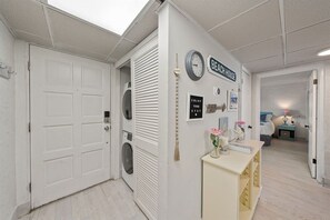 A laundry room with a washing machine, a dryer, and a wall-mounted clock.