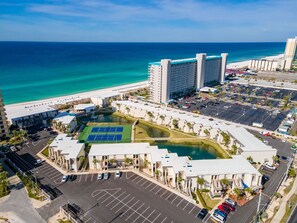 An aerial view of a hotel with a tennis court, parking lot, and ocean view. - Beachfront | 2BR 2BA | Pool | Pet Friendly (Panama City Beach)