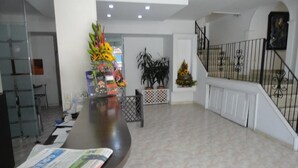 A spacious lobby with a reception desk, a staircase, and potted plants. - HOTEL FENIX REAL (Bogotá)