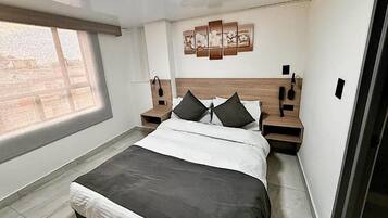 Un dormitorio moderno con una cama grande, dos mesitas de noche, un cuadro en la pared y una ventana con persianas.