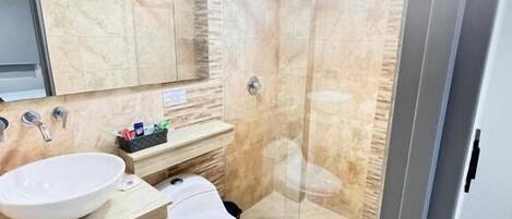 A modern bathroom with a glass-enclosed shower, a large sink, and a toilet.