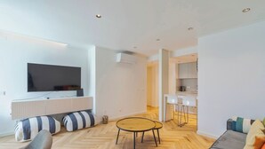 A modern living room with a flat-screen TV, striped cushions, a round coffee table, and a sofa with colorful cushions. - Avenue Centro Casa, Setúbal (Setúbal)
