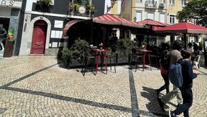 A cobblestone courtyard with outdoor seating, a red door, and a building with striped awnings. - Avenue Centro Casa, Setúbal (Setúbal)