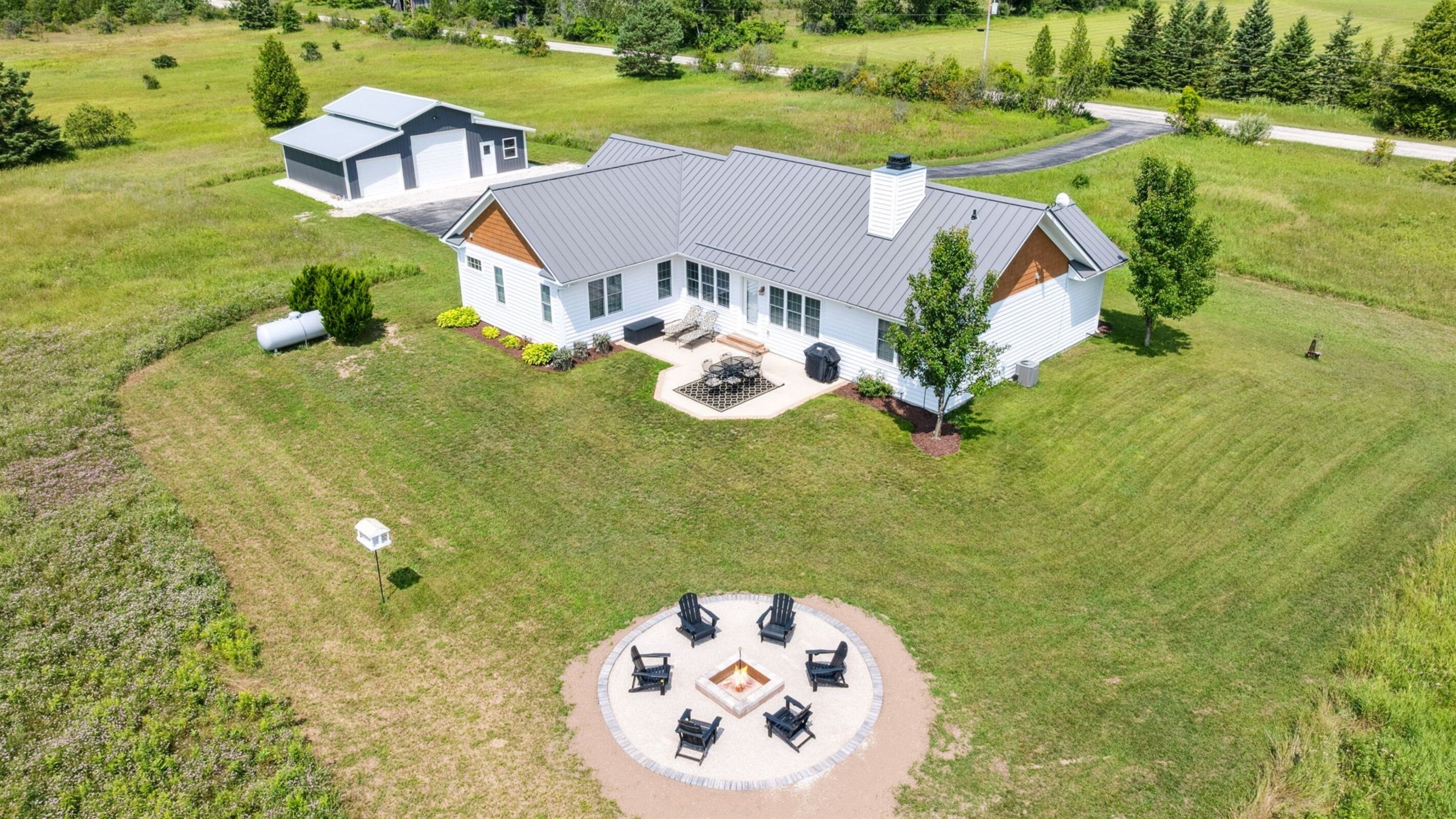 A large house with a spacious backyard, a fire pit, and outdoor seating.