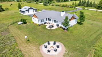 A large house with a spacious backyard, a fire pit, and outdoor seating.