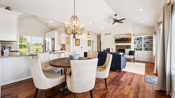 A spacious kitchen with a dining area, a fireplace, and a ceiling fan.