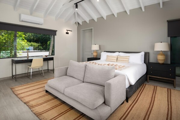 A modern bedroom with a bed, a sofa, a desk, and a chair.