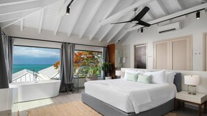 A modern bedroom with a large bed, a bathtub, and a view of the ocean. - Villa Eden, Modern Oceanfront Villa on Blue Mountain (Providenciales)