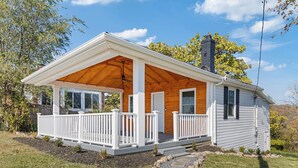 Eenlaags huis met een overdekte veranda, witte hekwerk en een schoorsteen.