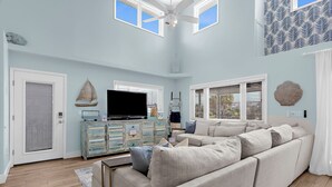 A spacious living room with a large sofa, a television, and a ceiling fan.