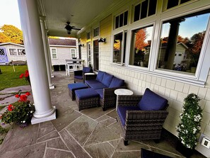 Un patio couvert aménagé avec des meubles en osier et un sol en pierre.