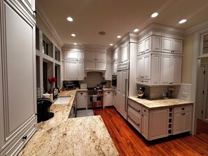 A kitchen with white cabinetry, a granite countertop, and a wooden floor.