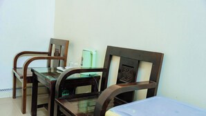 Un coin repas avec des chaises et une table en bois, un réfrigérateur et un four à micro-ondes.