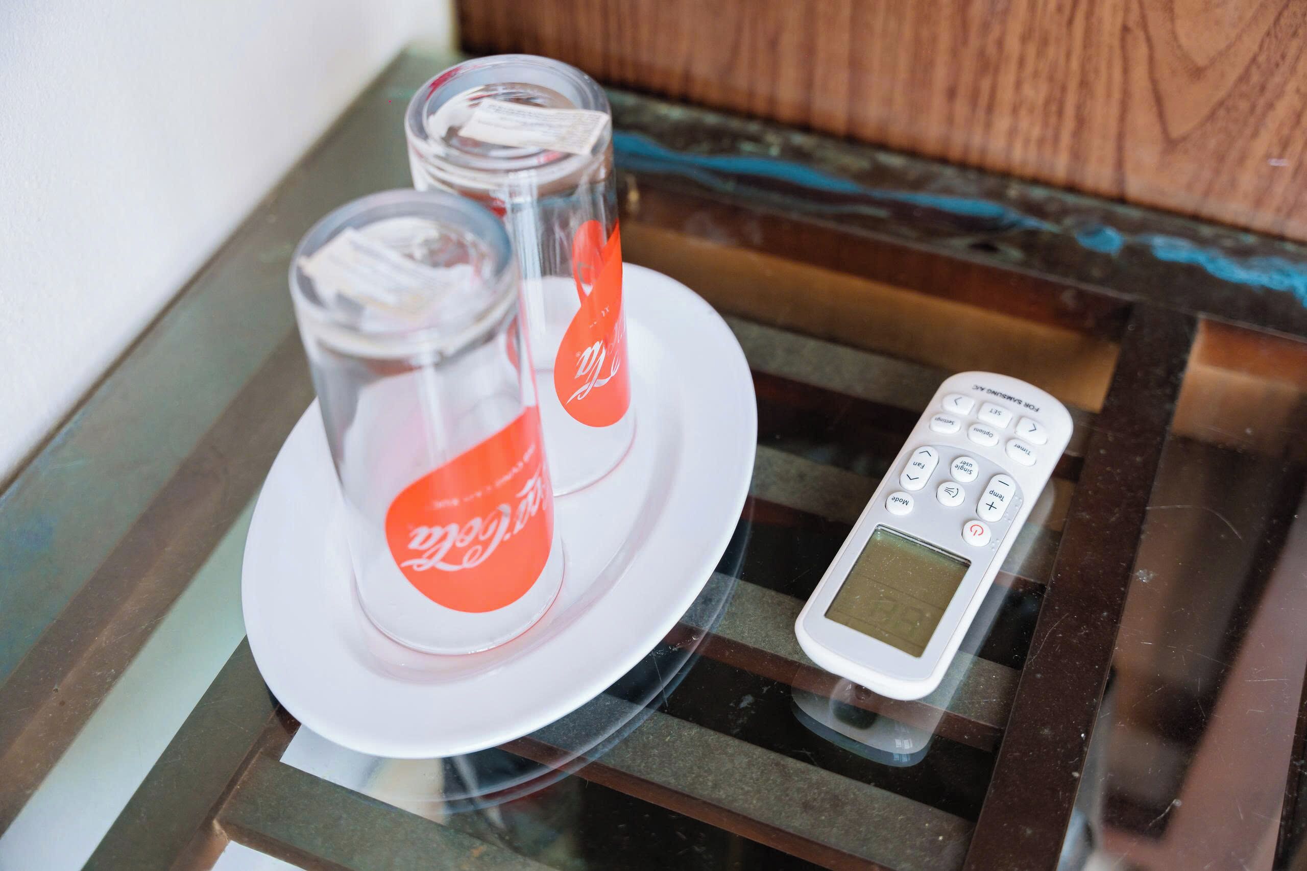 A glass table with two Coca-Cola bottles and a digital remote control.
