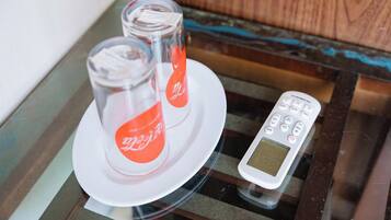A glass table with two Coca-Cola bottles and a digital remote control.