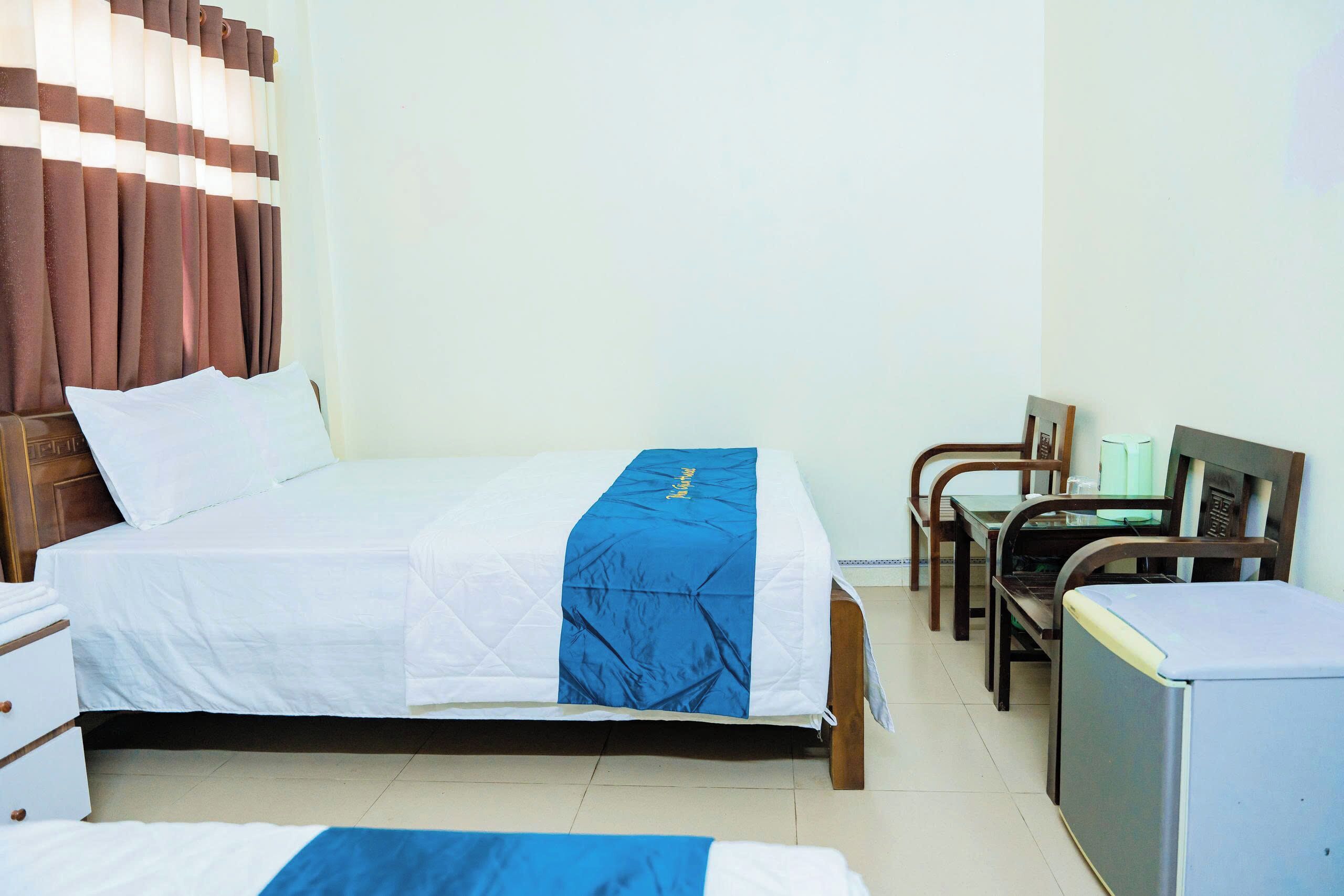 Habitación de hotel con cama, escritorio, silla y un refrigerador pequeño.