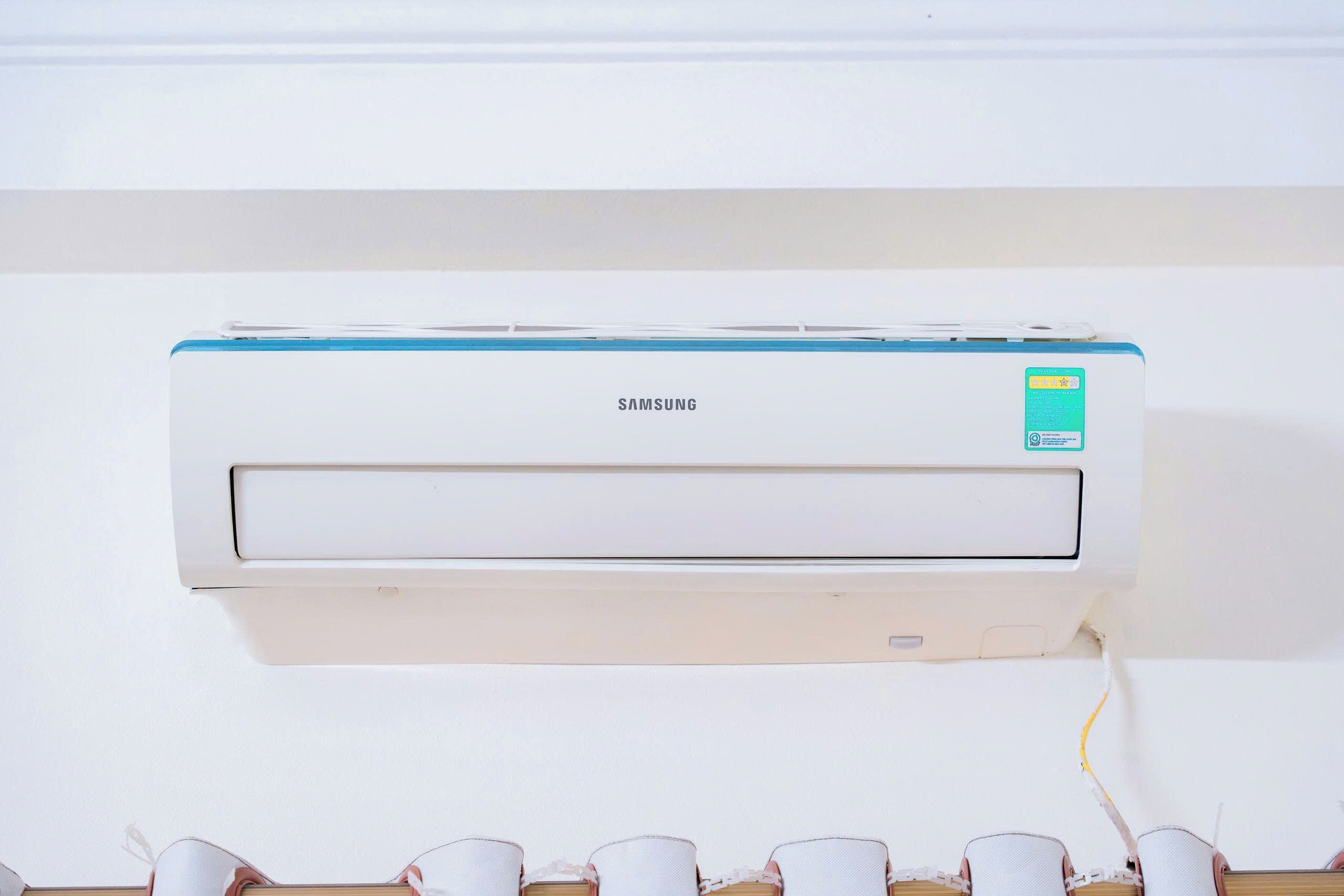 A white wall-mounted Samsung air conditioner with a green sticker on the right side.