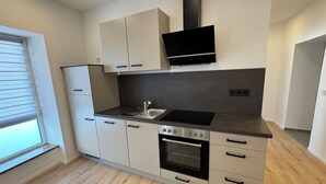 A modern kitchen with white cabinets, a black countertop, a built-in oven, and a flat-screen TV above the stove.